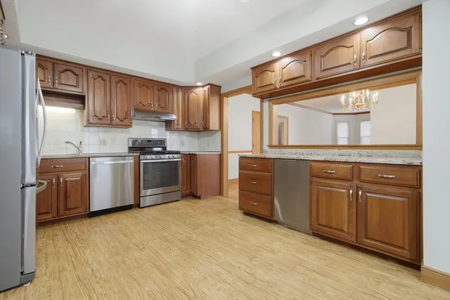 a kitchen with stainless steel appliances granite countertop a stove a sink and a refrigerator