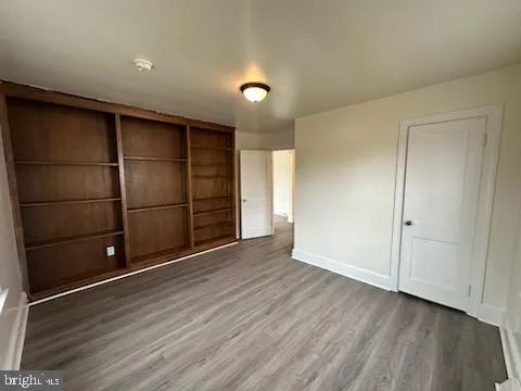 a view of an empty room with wooden floor and closet