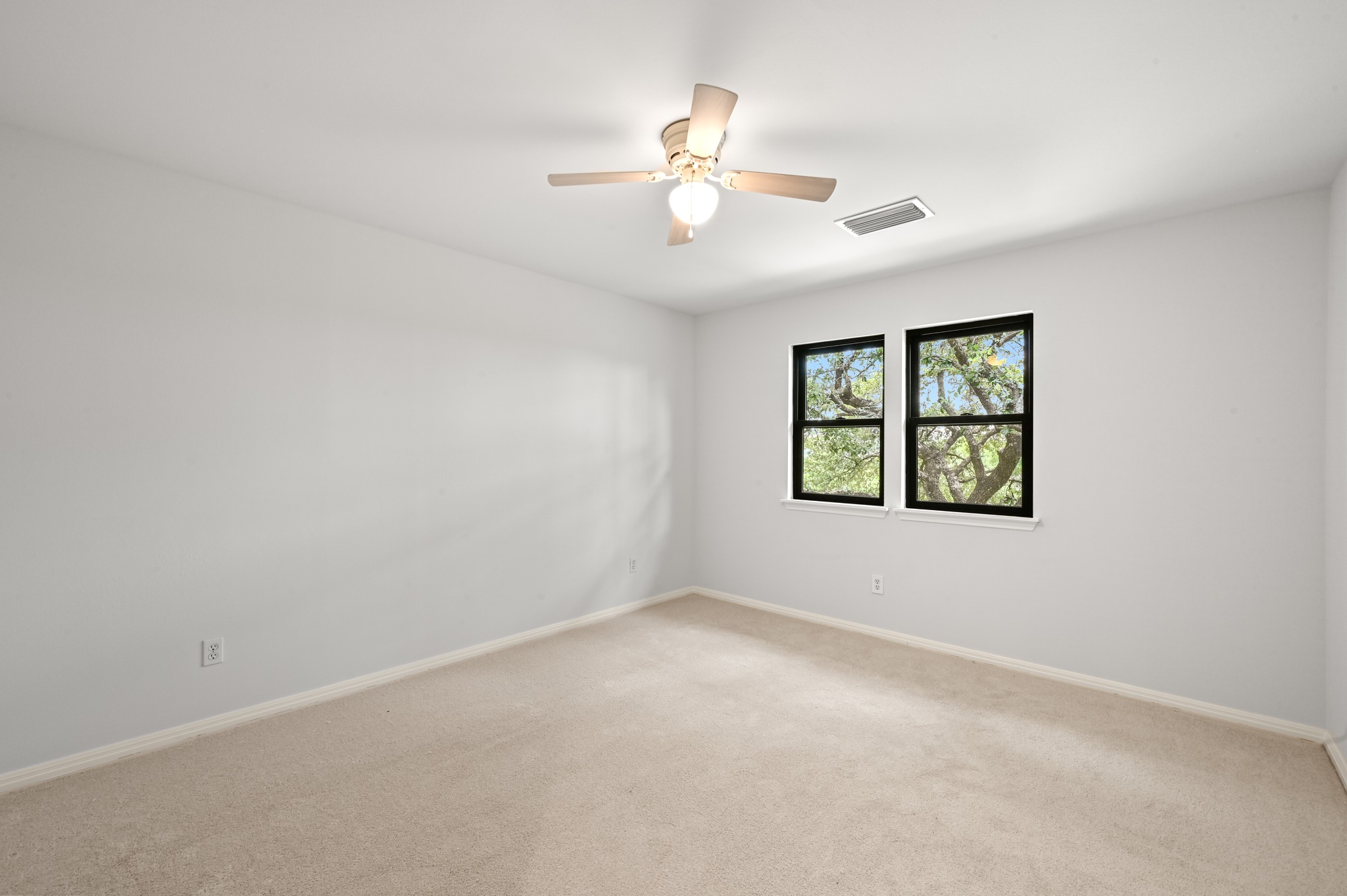 1107 Bowie Road Austin, TX 78733 - Photo 28 of 40 A well-lit bedroom features plush carpeting and tree-lined views through twin windows.