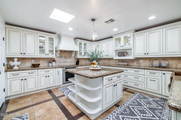 a kitchen with stainless steel appliances granite countertop a table chairs refrigerator and sink