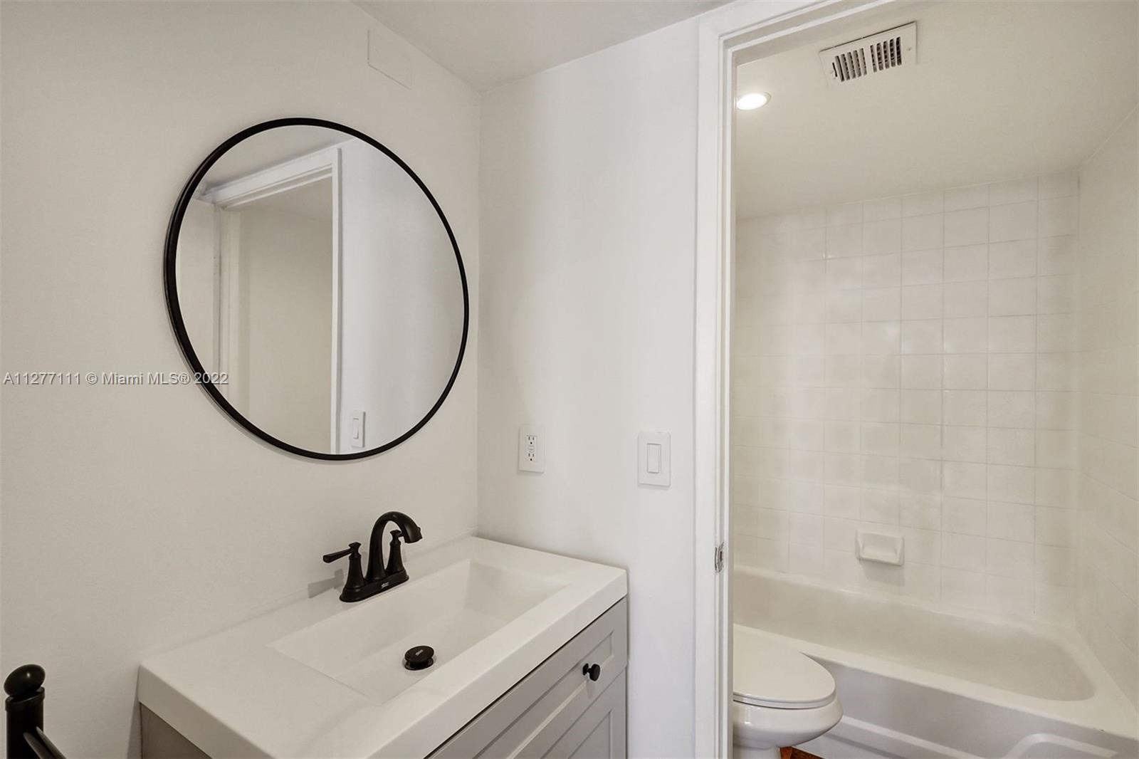 2351 Douglas Road, Unit 908 Miami, FL 33145 - Photo 23 of 37 a bathroom with a sink a toilet and a mirror