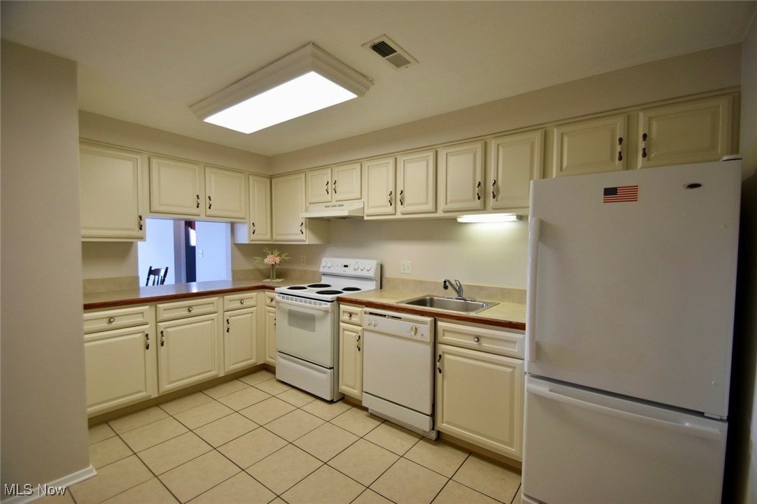 8955 West Ridge Road, Unit D Elyria, OH 44035 - Photo 7 of 33 Kitchen with white appliances, under cabinet range hood, light tile patterned floors, and light countertops