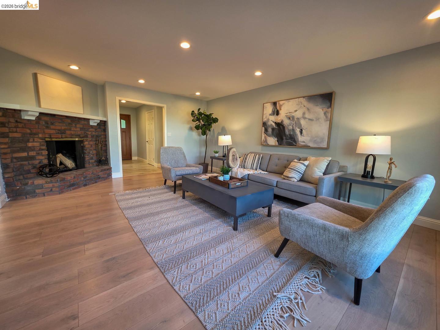 965 Springer Road Los Altos, CA 94024 - Photo 7 of 31 Spacious living area featuring wood-finish flooring, a brick-surround fireplace with a white mantel, recessed lighting, and light-toned wall finishes