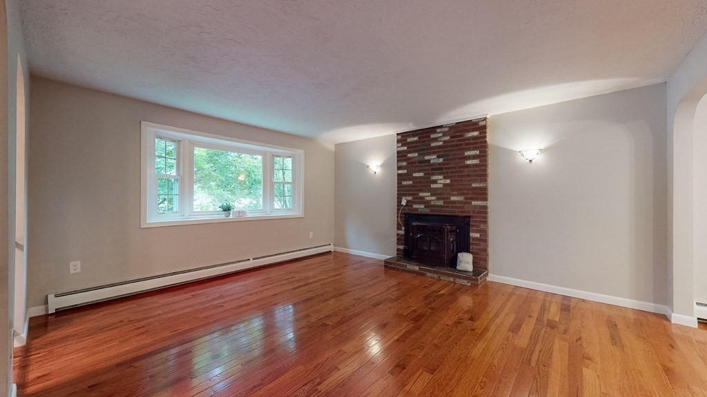 34 Heritage Road Sutton, MA 01590 - Photo 9 of 33 a view of an empty room with wooden floor fire place and windows