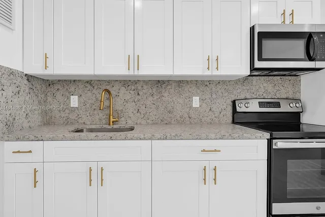 a kitchen with stainless steel appliances granite countertop white cabinets and a white stove