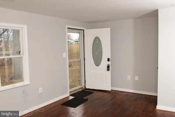 an empty room with wooden floor mirror and windows