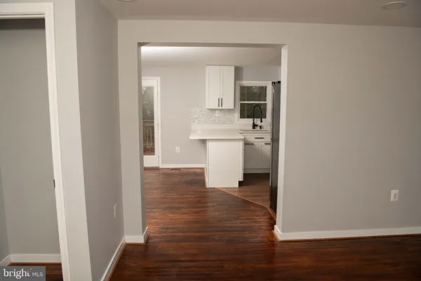 a view of a hallway with wooden floor and a bathroom