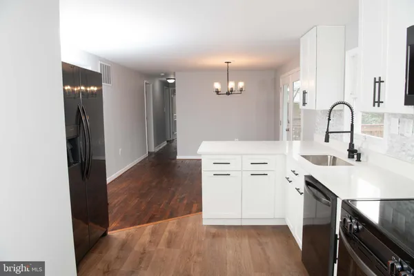 a hall with white cabinets and wooden floor