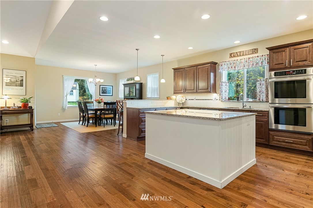 6800 Goodwin Road Everson, WA 98247 - Photo 11 of 40 a kitchen with kitchen island granite countertop wooden floors and stainless steel appliances