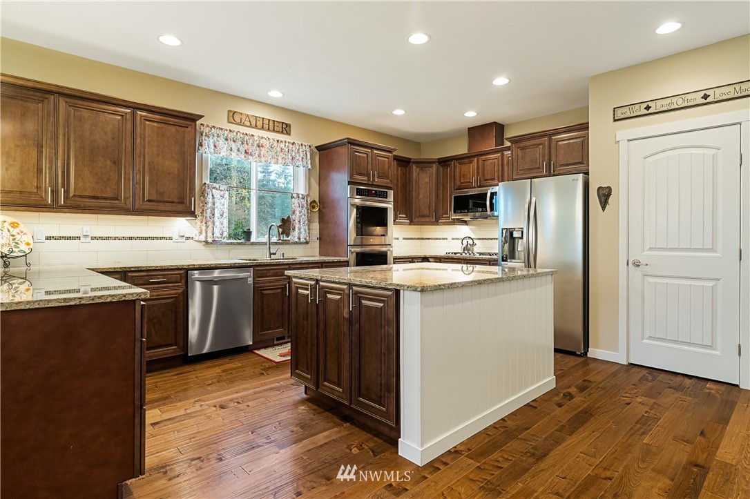 6800 Goodwin Road Everson, WA 98247 - Photo 14 of 40 a kitchen with stainless steel appliances granite countertop a refrigerator a sink dishwasher a stove and white cabinets with wooden floor