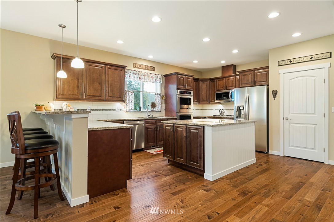 6800 Goodwin Road Everson, WA 98247 - Photo 15 of 40 a kitchen with kitchen island a sink a stove a refrigerator and chairs