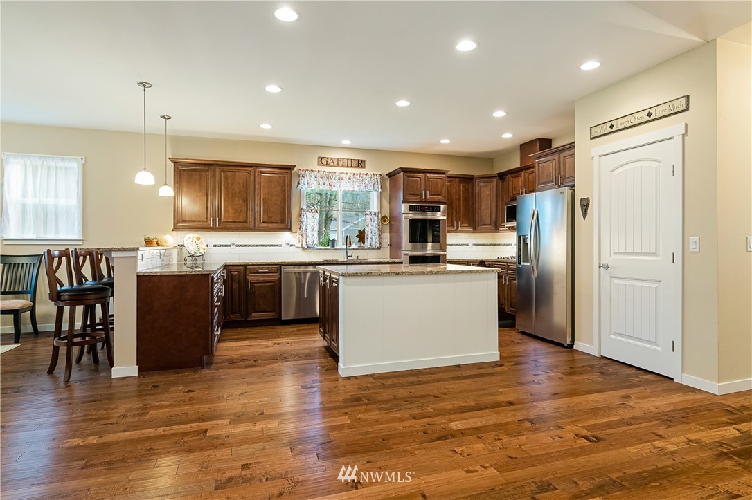 6800 Goodwin Road Everson, WA 98247 - Photo 10 of 40 a kitchen with stainless steel appliances kitchen island granite countertop a refrigerator a stove top oven a sink dishwasher and white cabinets with wooden floor