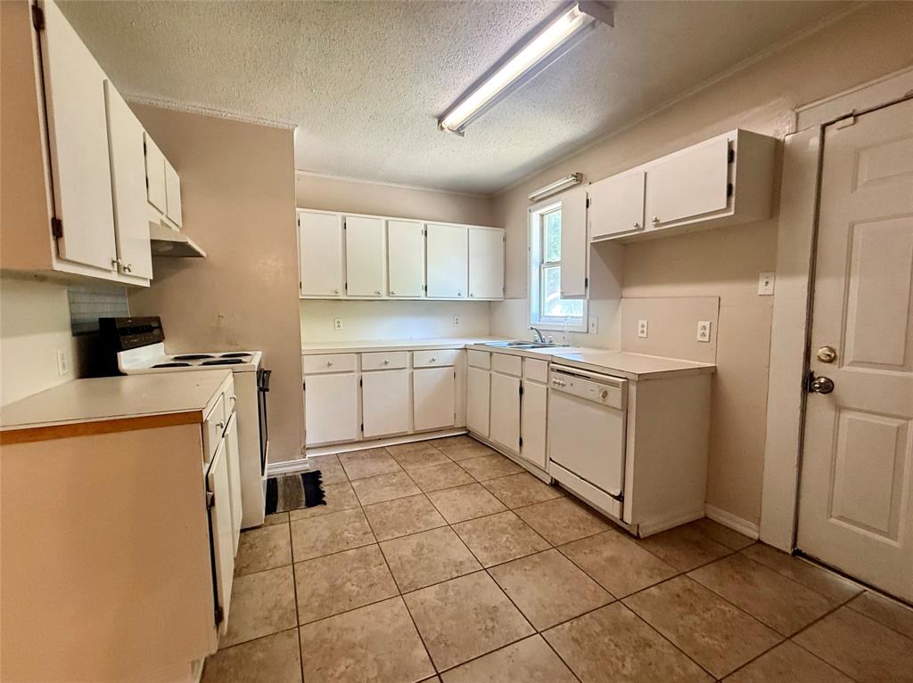 217 3rd St Pinehill Springhill, LA 71075 - Photo 15 of 23 Kitchen featuring extensive white cabinetry, a built-in dishwasher, tile flooring, a window above the sink, and an electric range