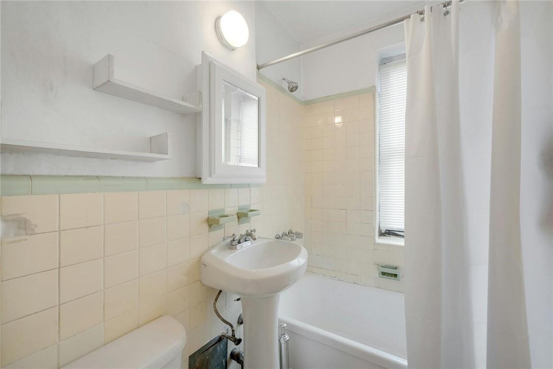 2025 Valentine Avenue, Unit 6B Bronx, NY 10457 - Photo 11 of 15 Full bathroom with shower / bathtub combination with curtain, toilet, sink, tile walls, and decorative backsplash