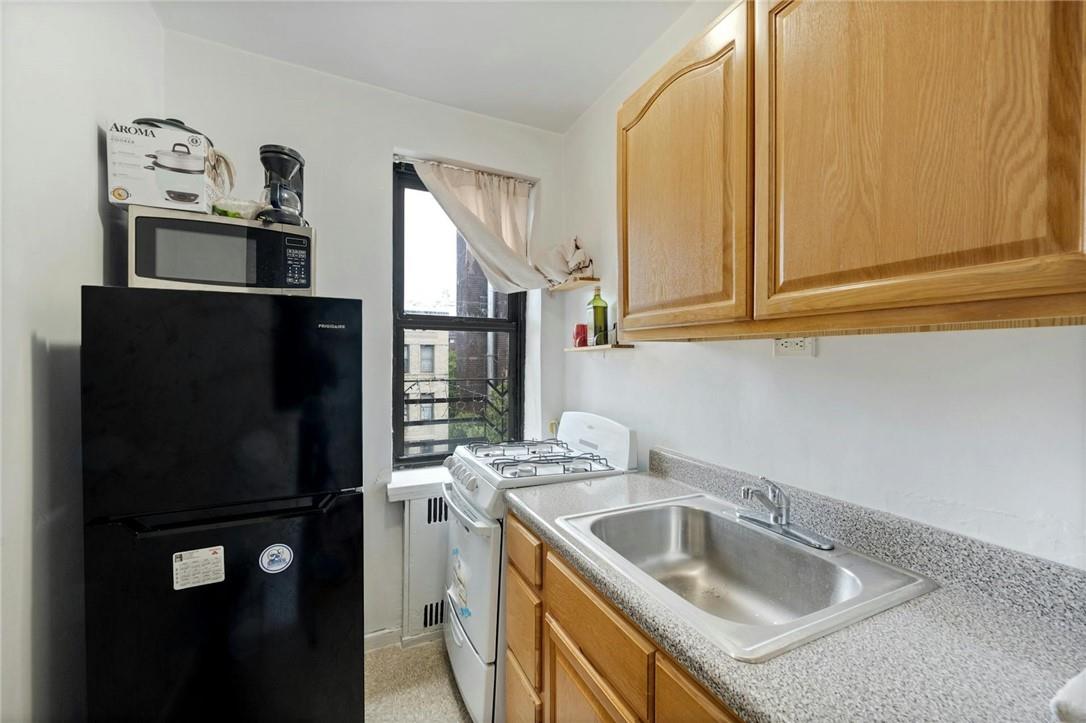 2025 Valentine Avenue, Unit 6B Bronx, NY 10457 - Photo 7 of 15 Kitchen featuring white range, black refrigerator, and sink