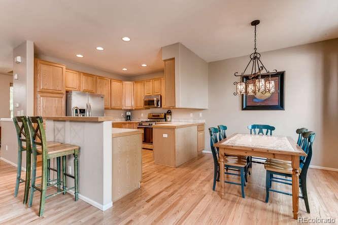 1672 Spring Water Place Highlands Ranch, CO 80129 - Photo 8 of 25 a kitchen with stainless steel appliances granite countertop a dining table chairs refrigerator and microwave