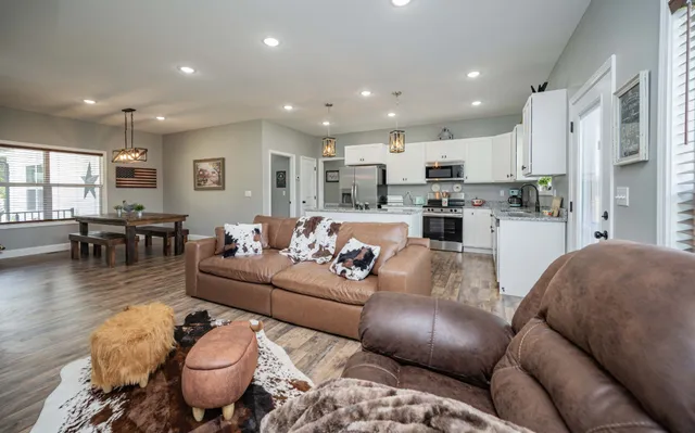 a living room with furniture kitchen view and a wooden floor