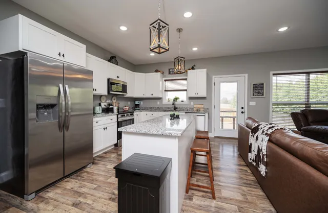 a large kitchen with stainless steel appliances kitchen island granite countertop a refrigerator a stove a sink a dining table and chairs with wooden floor