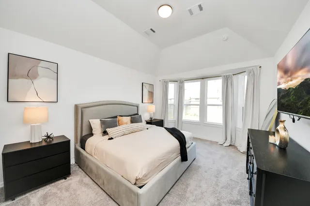 a large bedroom with a bed and a flat tv screen on the dresser