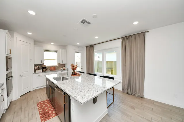 a large kitchen with granite countertop a large counter top appliances and cabinets