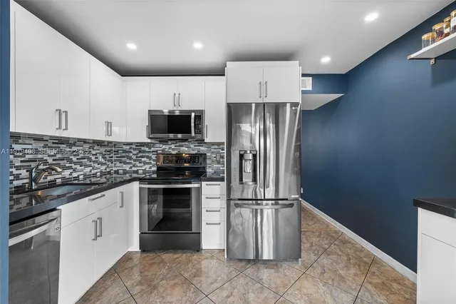 a kitchen with granite countertop a refrigerator and a stove top oven