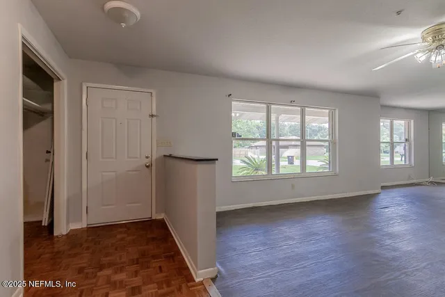 an empty room with wooden floor and windows