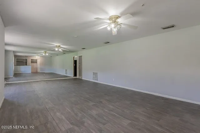 an empty room with wooden floor and chandelier fan