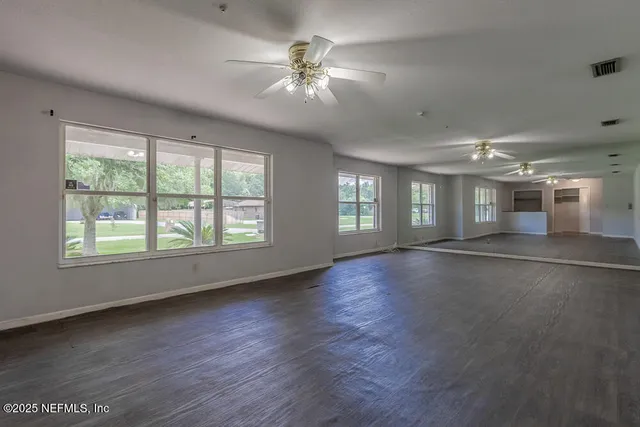 a view of an empty room with window and wooden floor