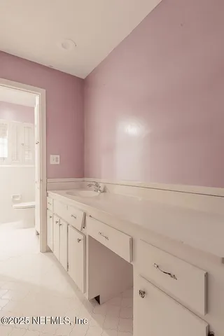 a spacious bathroom with a granite countertop sink and white cabinets
