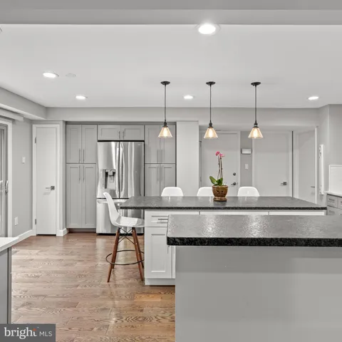 a view of a kitchen with kitchen island stainless steel appliances sink and wooden floor