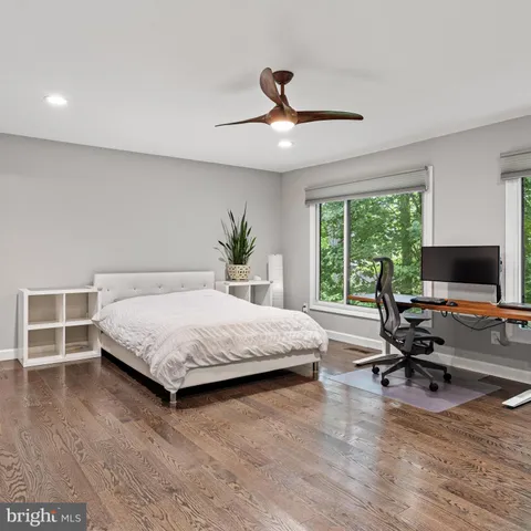 a spacious bedroom with a bed a chair and a large window