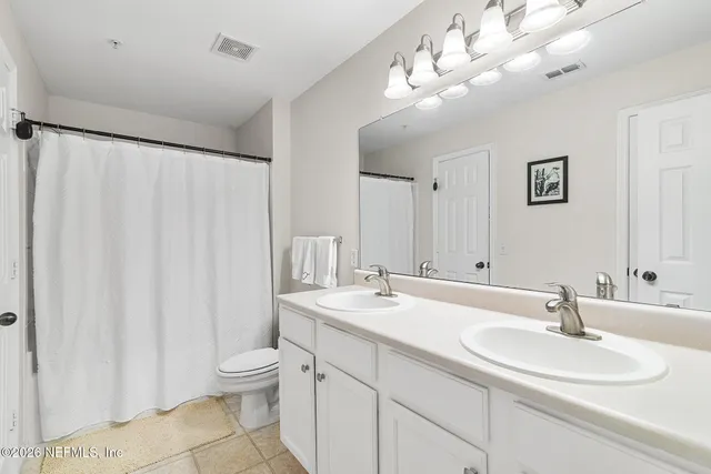 a bathroom with a double vanity sink mirror and toilet