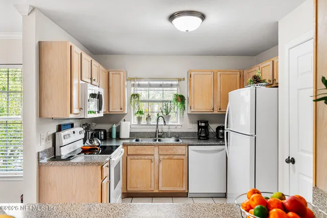 a kitchen with refrigerator a sink a stove and white cabinets