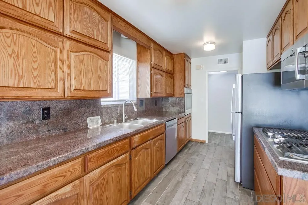 7568 Ohio Place La Mesa, CA 91942 - Photo 3 of 32 a kitchen with stainless steel appliances granite countertop a stove a sink and a refrigerator
