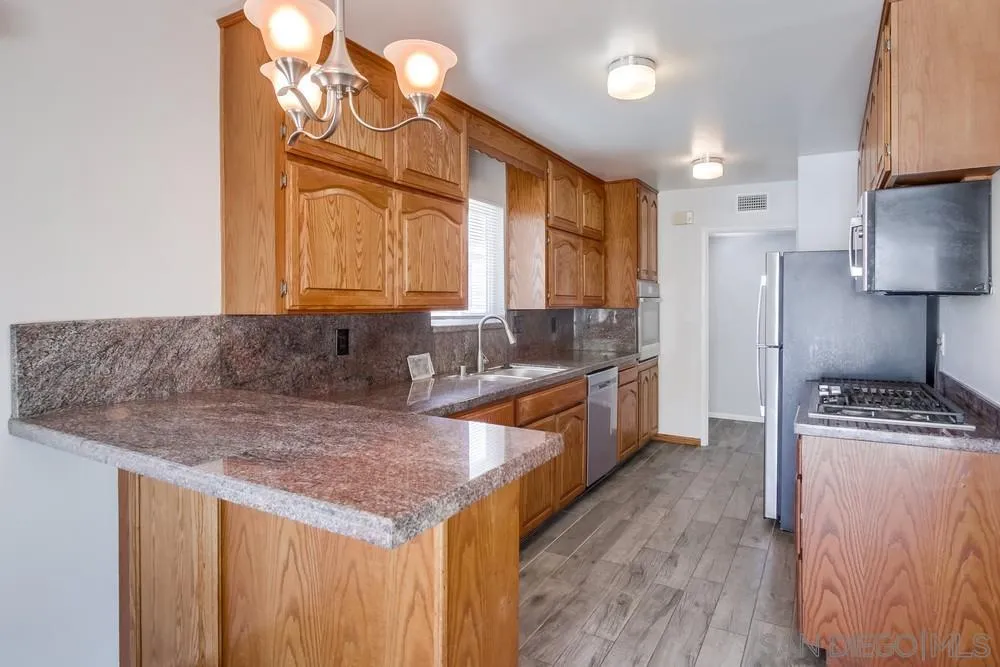7568 Ohio Place La Mesa, CA 91942 - Photo 7 of 32 a kitchen with granite countertop a stove a sink and a refrigerator