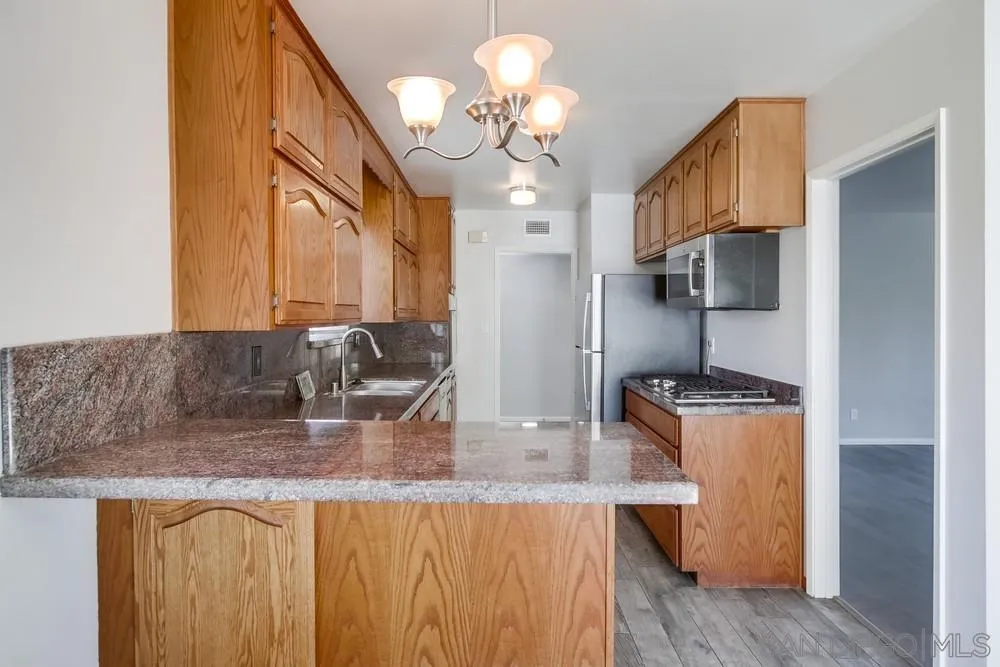 7568 Ohio Place La Mesa, CA 91942 - Photo 8 of 32 a kitchen with stainless steel appliances granite countertop a sink a stove and a refrigerator