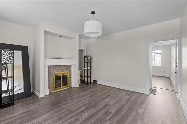 a view of an empty room with wooden floor fireplace and a window