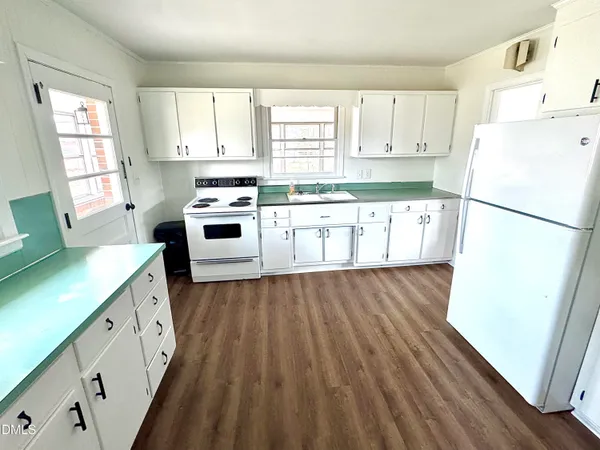 a kitchen with a sink a stove a refrigerator and white cabinets