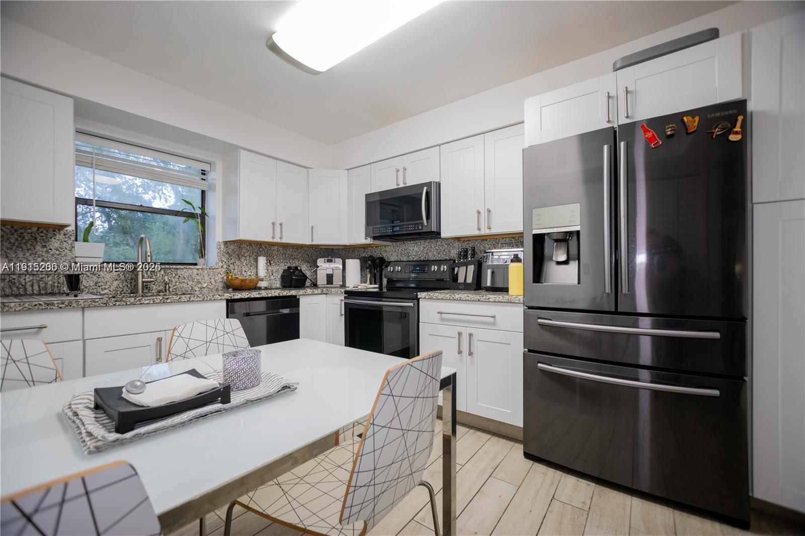 16100 Golf Club Road, Unit 202 Weston, FL 33326 - Photo 15 of 31 a kitchen with stainless steel appliances white cabinets and wooden floor
