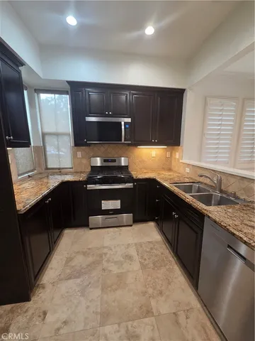 a kitchen with stainless steel appliances granite countertop a stove a sink and a microwave