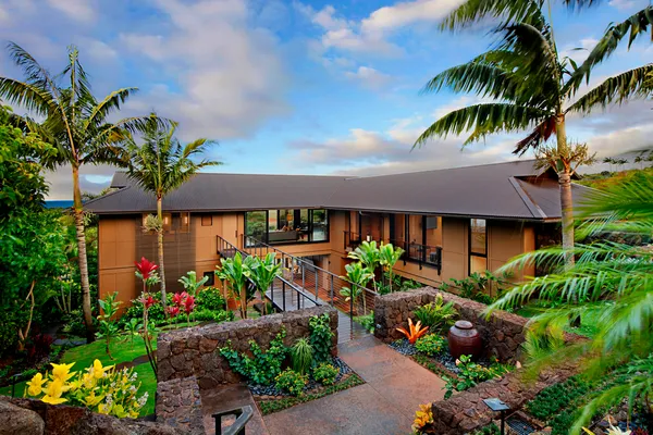 a front view of a house with a lot of flower and trees