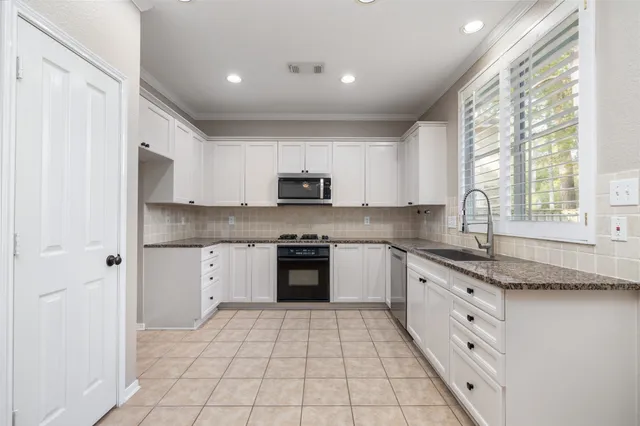 a kitchen with stainless steel appliances granite countertop white cabinets granite counter tops and a window