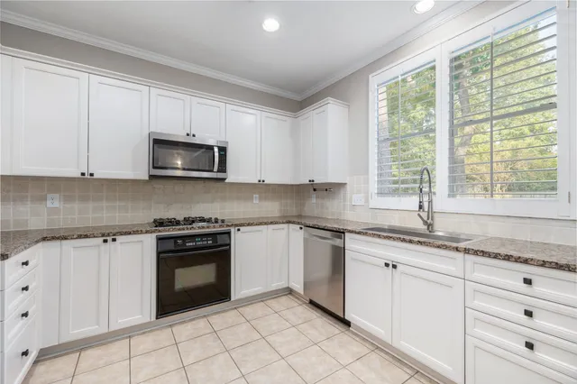 a kitchen with granite countertop white cabinets a sink and a stove with wooden floor