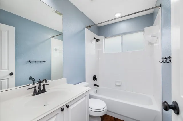a bathroom with a bathtub shower sink vanity mirror and toilet