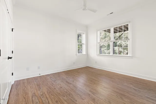 an empty room with wooden floor and windows