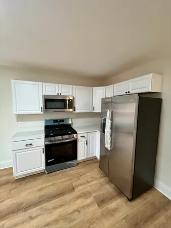 a large kitchen with cabinets wooden floor and stainless steel appliances