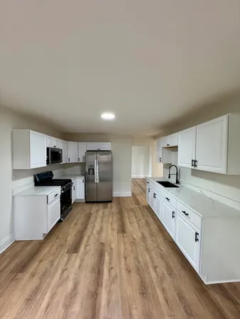 a view of a hallway with wooden floor and a bathroom