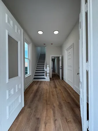 a view of a hallway with wooden floor and staircase