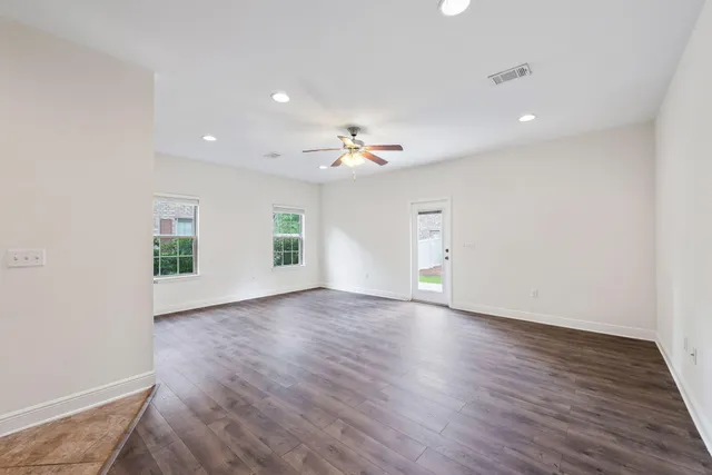 an empty room with wooden floor and chandelier fan