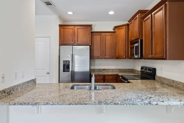 a kitchen with granite countertop wooden cabinets stainless steel appliances and a window